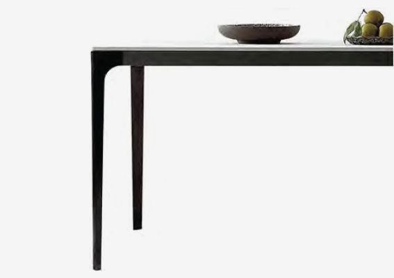 simple white desk on a white wall with a plant on the far right side